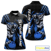 Load image into Gallery viewer, Front and back view of a black and mid blue women's bowling polo shirt displaying a roaring tiger holding a mid blue bowling ball with matching claw-stripe artwork and a geometric background pattern.