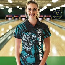 Load image into Gallery viewer, Front view of a female model at a bowling lane wearing a black and teal blue bowling polo shirt showcasing a roaring tiger holding a teal blue bowling ball with teal blue claw-stripe artwork and a geometric background pattern.