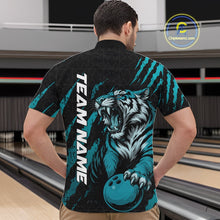 Load image into Gallery viewer, Male model wearing a black and teal blue bowling quarter-zip shirt in a bowling lane featuring a roaring tiger holding a teal blue bowling ball with teal blue claw-stripe artwork and a geometric background pattern.