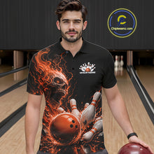 Load image into Gallery viewer, Front view of a male model in a bowling alley wearing a black bowling polo shirt featuring an orange fiery skull design with lightning striking a bowling ball and pins and a custom name.
