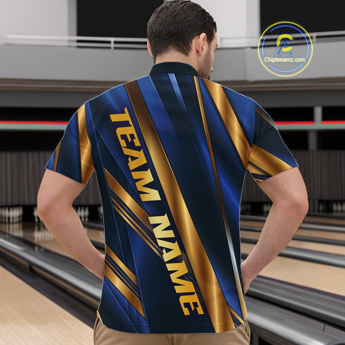 A man viewed from behind wearing a short-sleeve bowling shirt with a blue and gold striped pattern and 'TEAM NAME' printed vertically on the back, standing in a bowling alley. A 'Chipstreamz.