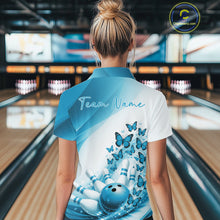 Load image into Gallery viewer, Back view of a female model wearing a white and blue bowling polo with butterfly artwork and bowling graphics at the bowling lane