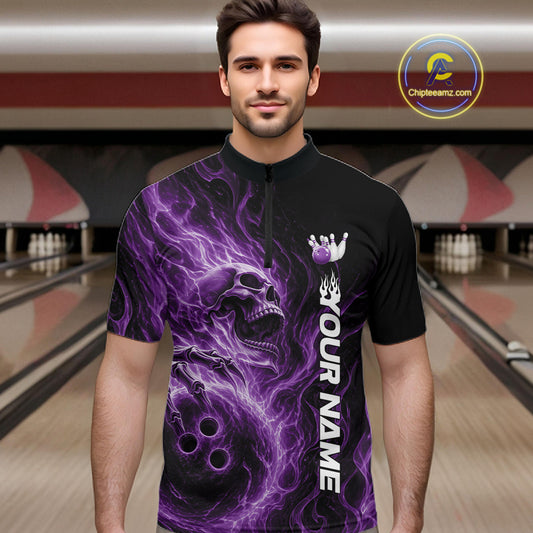 Male model wearing a black bowling quarter-zip shirt in a bowling alley featuring a skull clutching a bowling ball with swirling purple energy flames