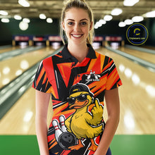 Load image into Gallery viewer, Female model at a bowling alley wearing a black and orange polo decorated with duck artwork, bowling pins, and geometric patterns.