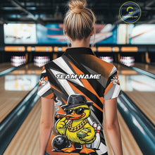 Load image into Gallery viewer, Back view female model in bowling lane wearing black and orange quarter zip featuring duck with sunglasses and fedora holding cash and cigar beside bowling ball and pins artwork.