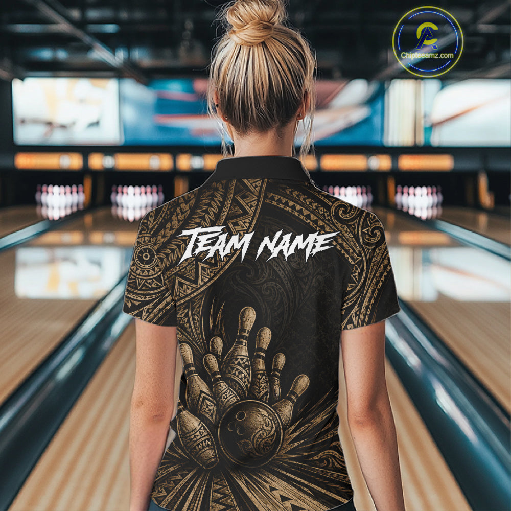 A woman viewed from behind wearing a black short-sleeve bowling-themed shirt with a large gold hand graphic and the words 'TEAM NAME' across the back, standing in a bowling alley.