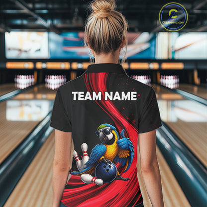 A woman viewed from behind wearing a black short-sleeve bowling-themed polo shirt with a large back graphic showing a blue and yellow macaw, bowling pins, a bowling ball, and red swooshes. The shirt has 'TEAM NAME:' printed in white across the upper back.
