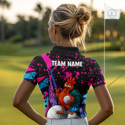 A woman on a golf course seen from behind, wearing a black short-sleeve polo shirt with a colorful graphic print of a cartoon rooster and golf balls, plus 'TEAM NAME' text on the back. A golf flag is visible in the background.