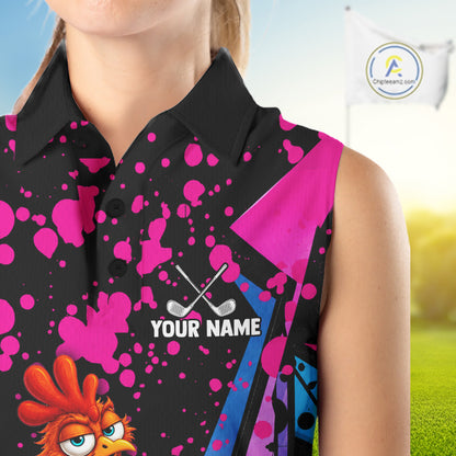 A sleeveless black polo-style top with bright pink paint splatter graphics, a blue side panel, crossed golf clubs graphic, and a cartoon rooster illustration, shown on a cropped model against a blurred golf-course background. The shirt includes placeholder text 'YOUR NAME' and a visible 'Ogreweart.