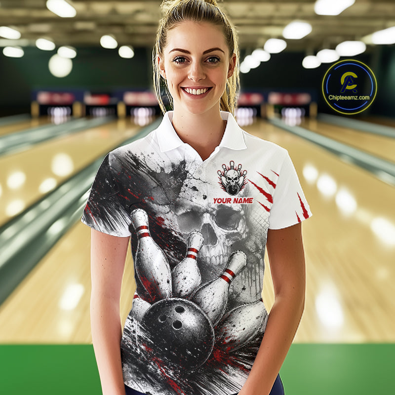 A woman wearing a custom bowling-themed polo shirt with a skull and bowling pins graphic, standing in a bowling alley. The shirt is white with a black and gray skull and bowling pins print, red claw marks, and 'YOUR NAME' text on the chest.