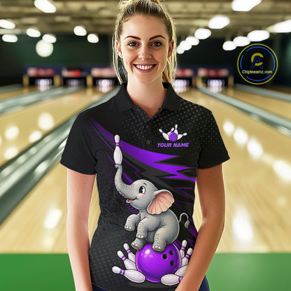 A woman stands in a bowling alley wearing a black short-sleeve polo shirt with a custom graphic of a cartoon elephant balancing a purple bowling ball on its trunk, with bowling pins and a bowler's strike pose. The shirt has a purple and black patterned design and the text 'YOUR NAME' with a bowling pin graphic.
