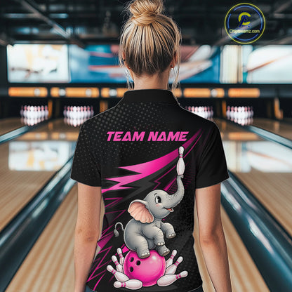 A woman viewed from behind wearing a black short-sleeve bowling-themed polo shirt with a pink and gray cartoon elephant graphic and the text 'TEAM NAME' on the back, standing in a bowling alley.