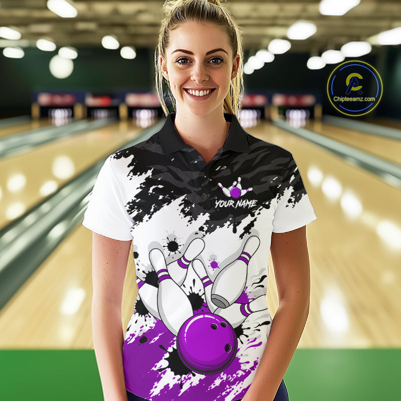 A woman wearing a custom bowling-themed polo shirt with a black and white paint splatter design, purple bowling pins and ball, and 'YOUR NAME' text, set against a blurred bowling alley background.