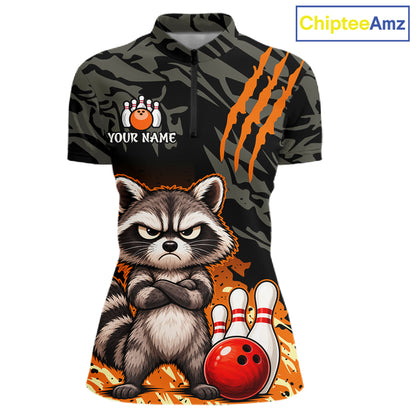 A women's short-sleeve polo shirt with a dark camouflage pattern, orange claw-stripe graphics, and a large cartoon raccoon holding a bowling ball and pins on the front. The shirt includes a placeholder bowling graphic and the text 'YOUR NAME' on the chest.