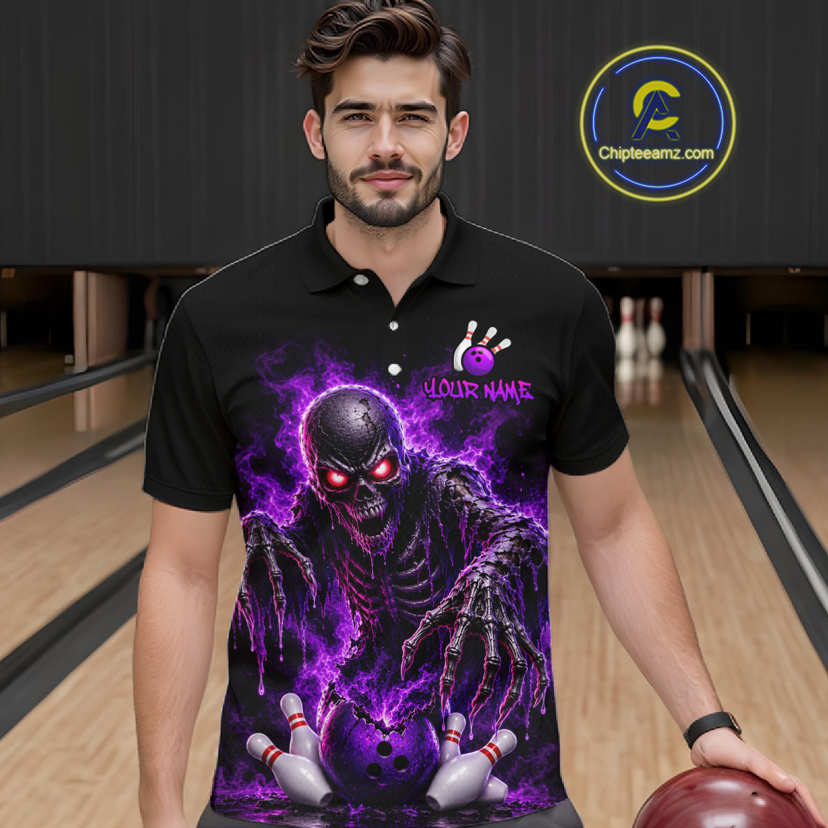 A man wearing a black short-sleeve polo shirt with a large purple and black horror graphic of a skull-faced monster reaching toward bowling pins, standing in a bowling alley.