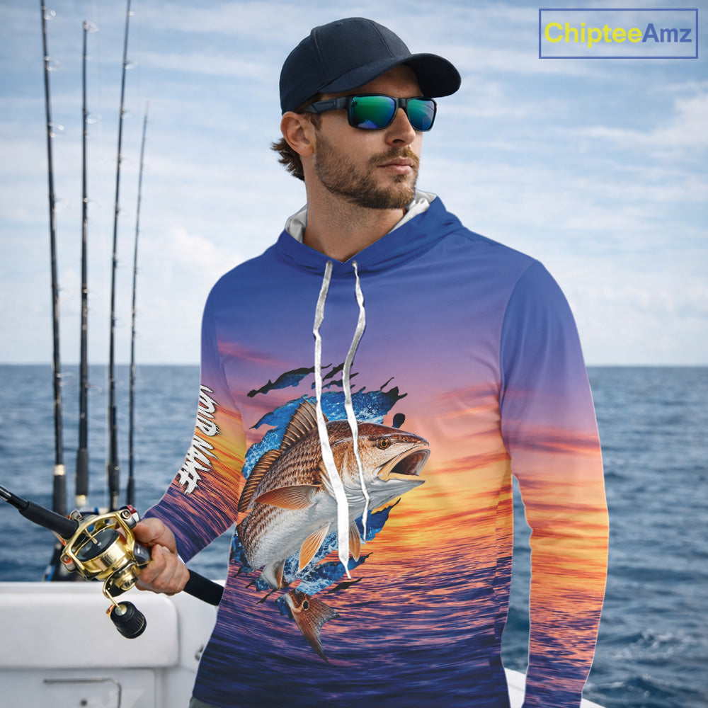 Angler wearing Redfish Fishing Sunset custom long sleeve hooded redfish offshore fishing shirt on the boat at sunset