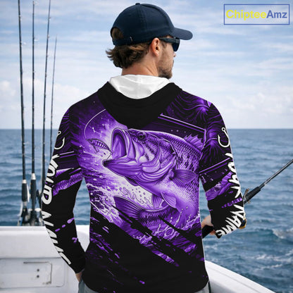 Person wearing a purple and black bass hooded fishing shirt with a fish design, standing by the ocean.
