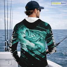 Load image into Gallery viewer, Person wearing a teal and black bass fishing shirt with a fish design, standing by the ocean.