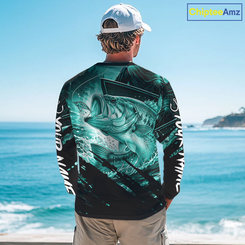 Person wearing a teal and black bass fishing shirt with a fish design, standing by the ocean.