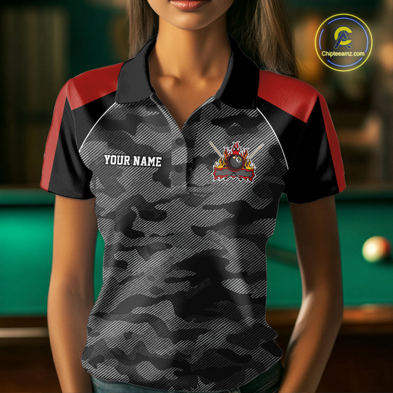 Woman wearing a grey camouflage American flag 8 ball billiard jersey beside a pool table front view.