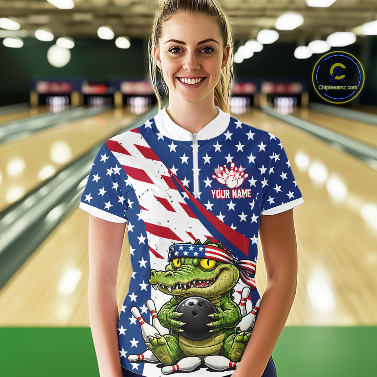 Person wearing a bowling shirt with an alligator holding a bowling ball design and American flag, in a bowling alley.