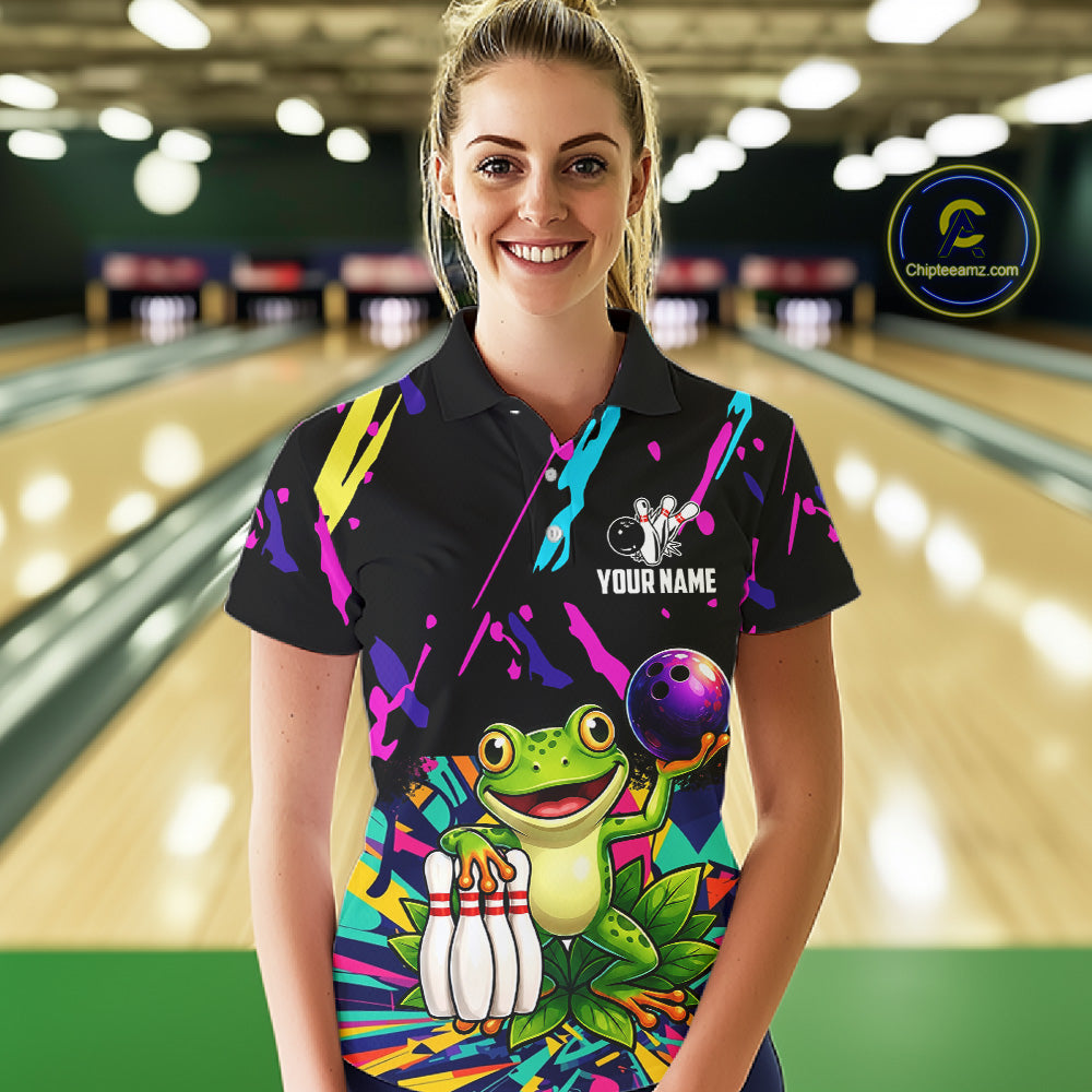 Woman wearing a colorful bowling-themed shirt with a frog graphic in a bowling alley.