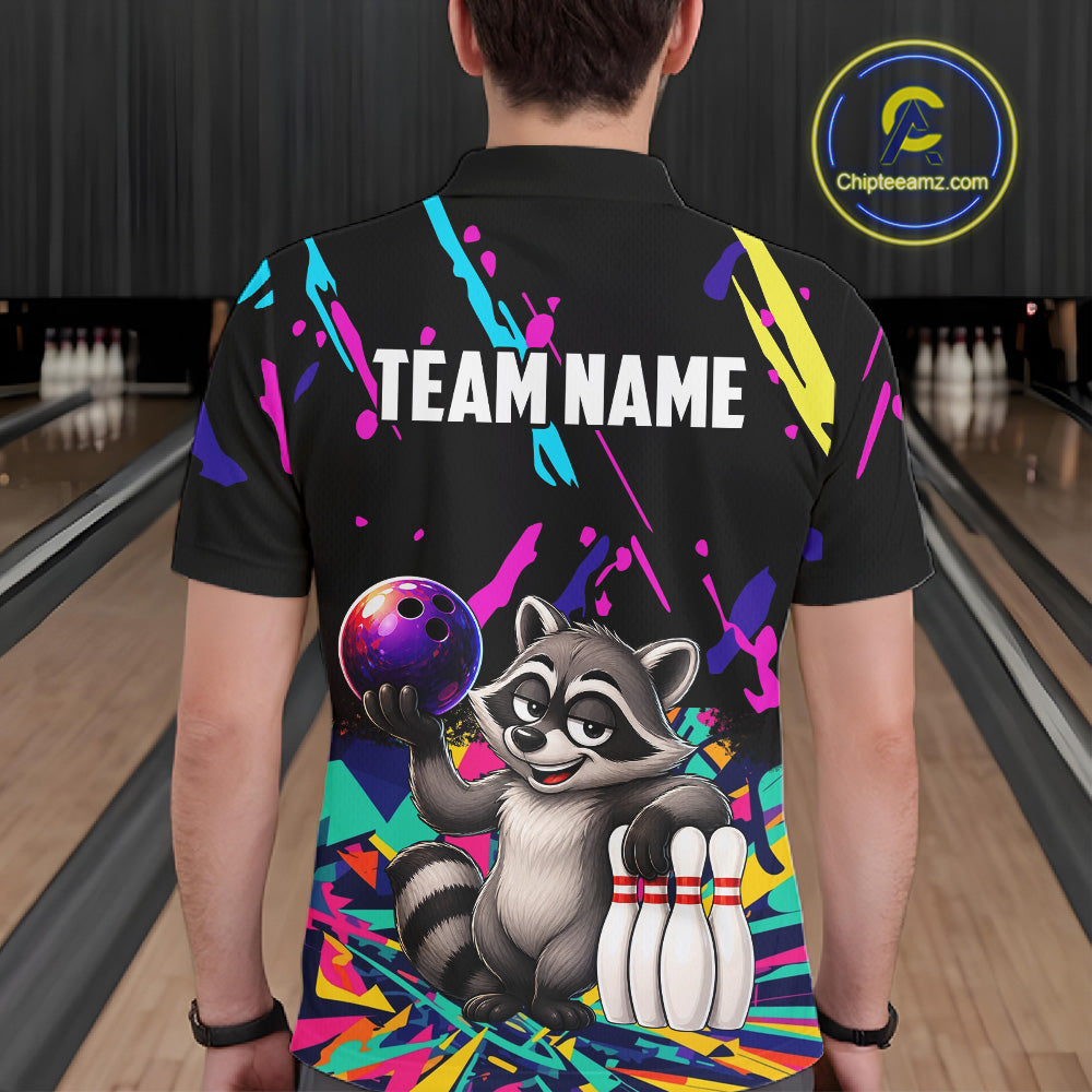 Person wearing a black bowling shirt with colorful design and raccoon graphic in a bowling alley.