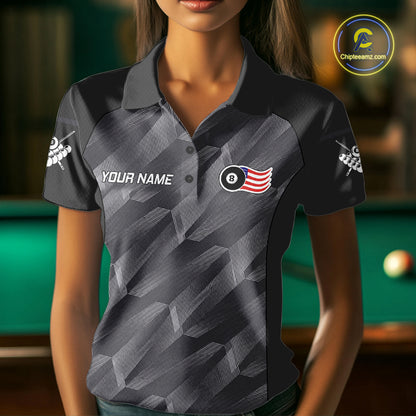 Woman wearing a metal grey American flag 8 ball billiard jersey beside a pool table front view.