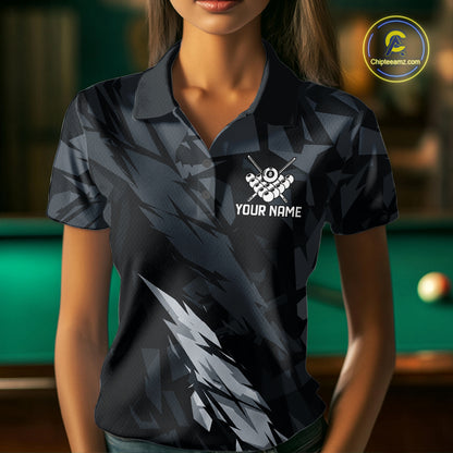 Woman wearing a black and grey billiard jersey beside a pool table front view.